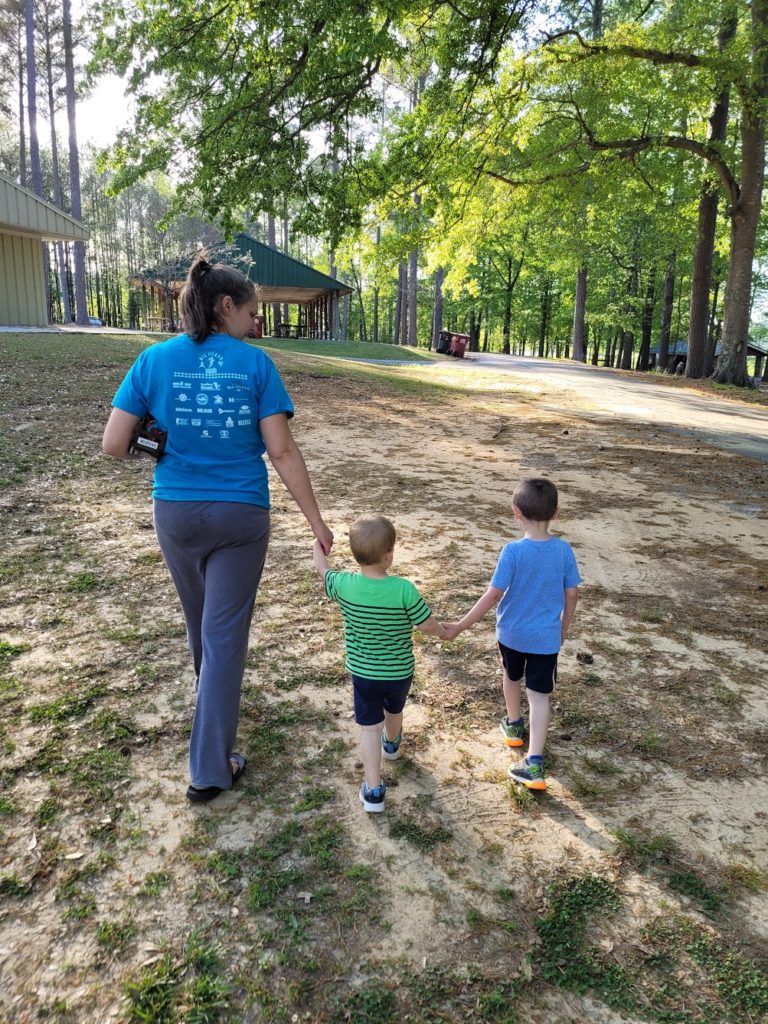 How to help your kids fall in love with prayer blog post - picture of mom and two young boys all holding hands walking in the park.